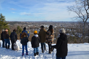 Group of walkers on Prospect Hill in Waltham. In the background are Waltham and the Boston skyline.