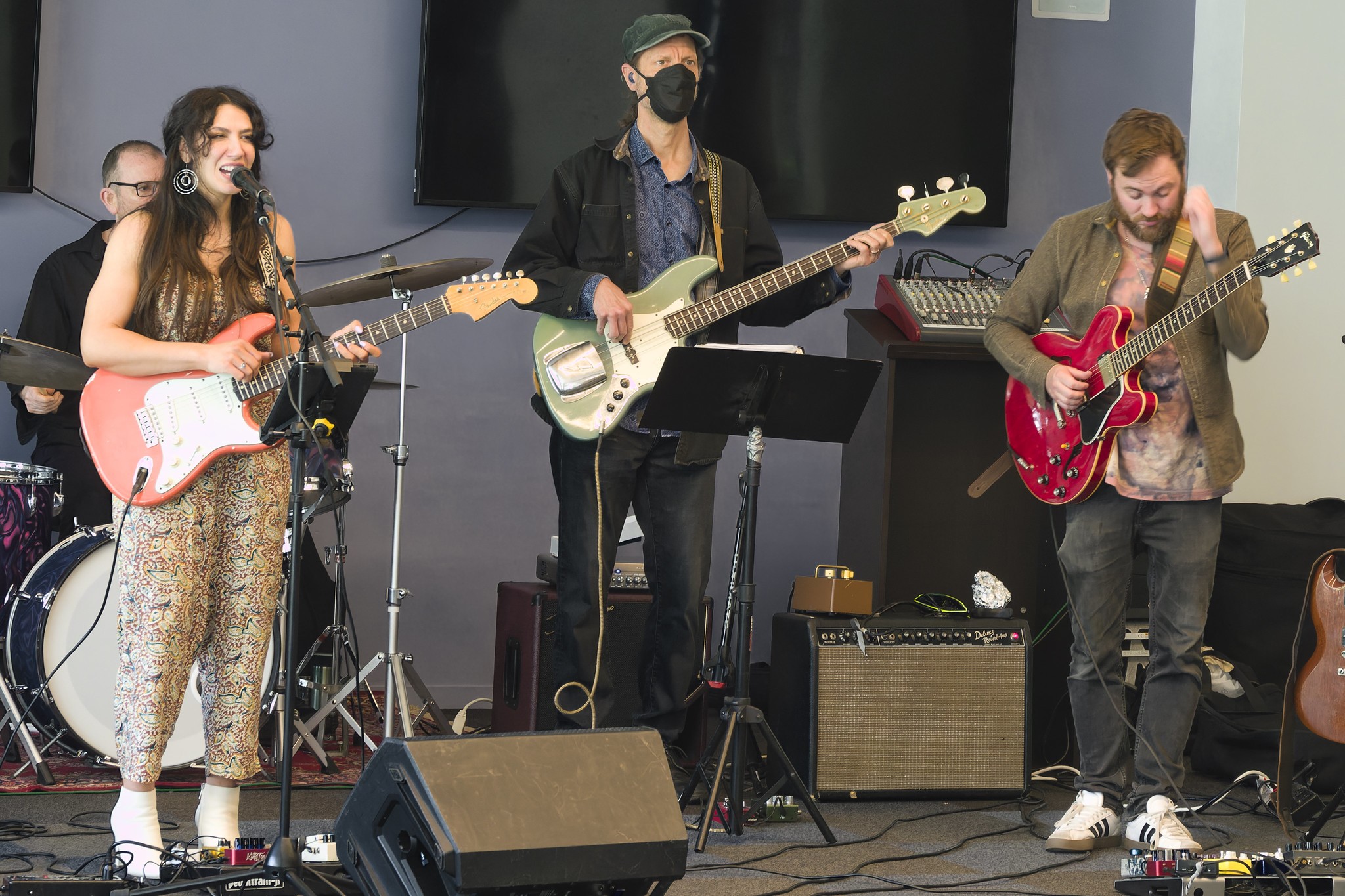 Three people play electric guitars on small stage.